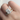 Close-up of a hand wearing two diamond rings on a light background